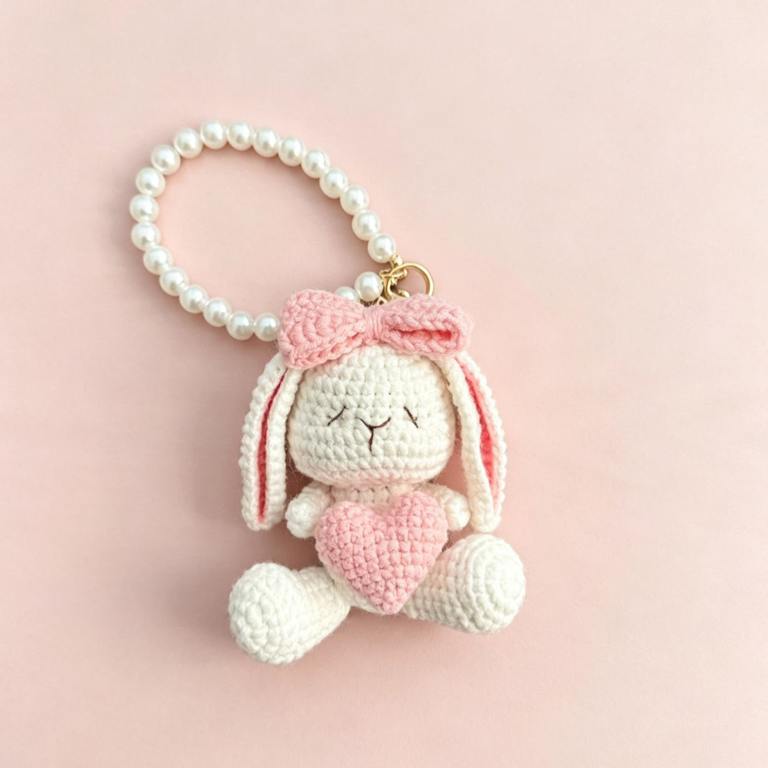 Crochet bunny holding a red flower with a pearl-look beaded loop