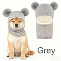 Grey knitted dog hood with double pom-poms, shown on a dog and separately