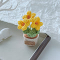 Pale blue crochet flowers in a miniature cream pot.
