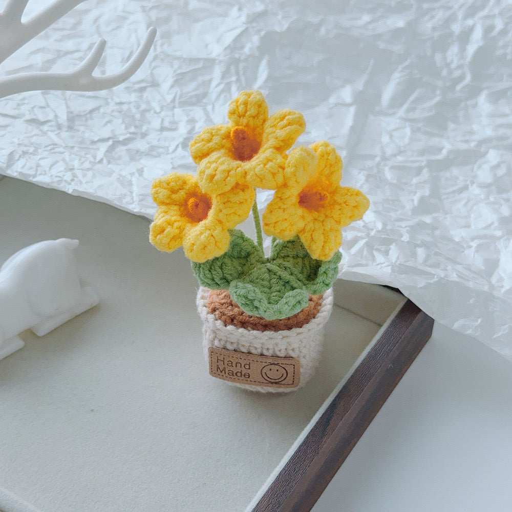 Pale blue crochet flowers in a miniature cream pot.