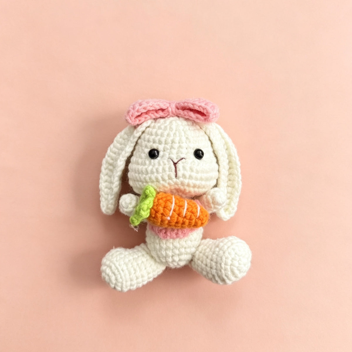 Crochet bunny holding a red flower with a pearl-look beaded loop